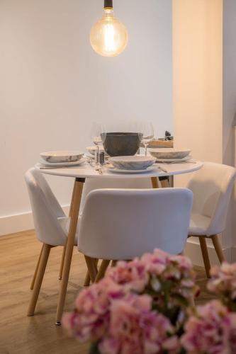 a dining room table with white chairs and a white table with flowers at Host & Stay - Osbourne Rest in Brighton & Hove