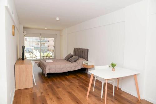 ein Schlafzimmer mit einem Bett und einem Tisch in einem Zimmer in der Unterkunft Belgrano amplio luminoso, cochera, WiFi, cerca River y Subte, 309 in Buenos Aires