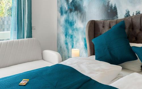 a bedroom with a bed with blue and white pillows at Lit Living Deluxe Apartments Wörth - Parking - Box Spring - BBQ - Balcony in Wörth am Rhein