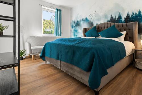 a bedroom with a large bed with a blue blanket at Lit Living Deluxe Apartments Wörth - Parking - Box Spring - BBQ - Balcony in Wörth am Rhein