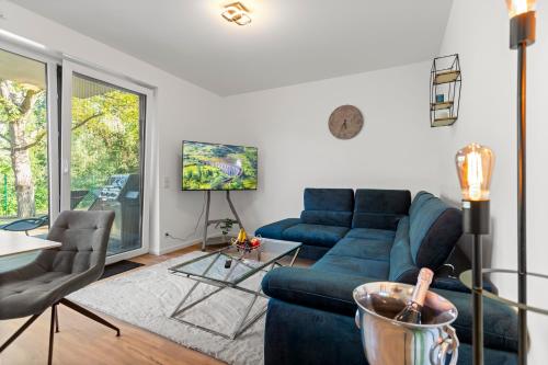 a living room with a blue couch and a tv at Lit Living Deluxe Apartments Wörth - Parking - Box Spring - BBQ - Balcony in Wörth am Rhein