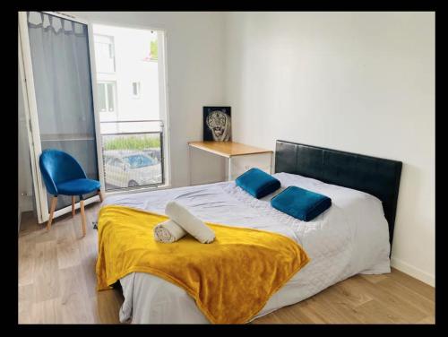 une chambre avec un lit avec des oreillers bleus et une couverture jaune dans l'établissement Cosy Appart, à Stains