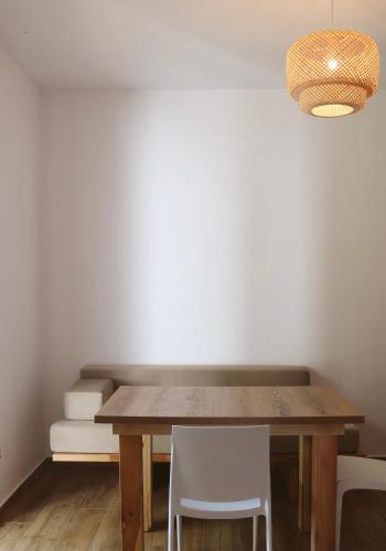 a dining room with a wooden table and white chairs at NOIMA Hotel & Suites in Velipojë