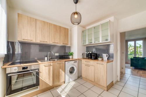 une cuisine avec des armoires en bois et une laveuse et une sécheuse dans l'établissement Le Grand Voyageur - 3 chambres - Parking privé - Métro, à Vénissieux