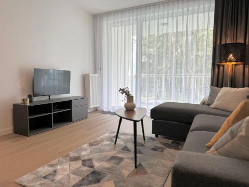 a living room with a couch and a tv and a table at Apartamenty Florina Q4Apartments in Łeba