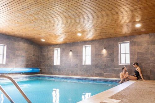 two women sitting next to a swimming pool at Killerby Old Hall with Hot Tub and Swimming Pool in Scarborough