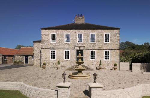 a large stone building with a fountain in front of it at Killerby Old Hall with Hot Tub and Swimming Pool in Scarborough