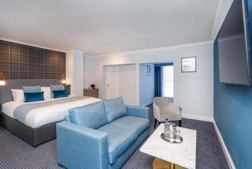 a hotel room with a bed and a blue couch at Bromley Court Hotel London in Bromley