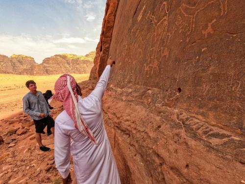 a man and a woman standing next to a rock wall at Stargazing Camp & Tours in Wadi Rum
