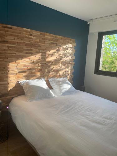 - une chambre avec un grand lit blanc et une tête de lit en bois dans l'établissement Charmant appartement Bordeaux, à Bordeaux