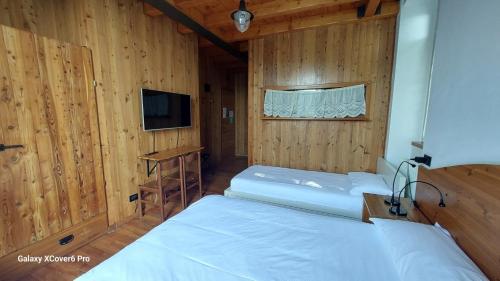 a bedroom with two beds and a tv in a room at Ristorante Hotel Falchetto in Brunate
