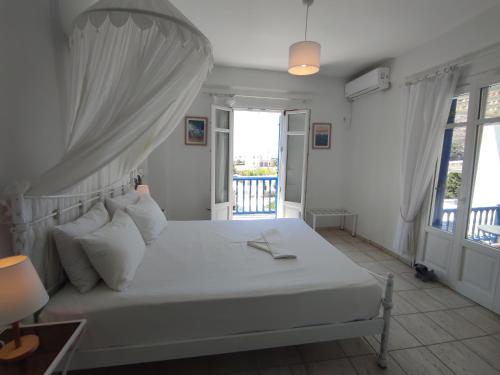 a bedroom with a white bed and a balcony at Villa Le Grand Bleu in Katapola