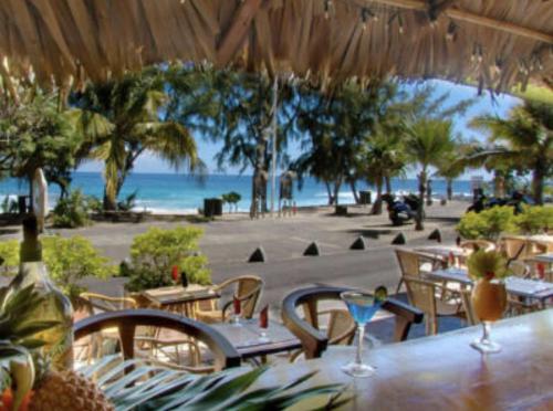 a restaurant with tables and chairs and the beach at COTTAGE BLUE classé 3 étoiles - 4 à 6 personnes - 2 chambres - accès direct à la plage et à l'esplanade de Boucan Canot avec ses bars et restaurants in Saint-Gilles les Bains