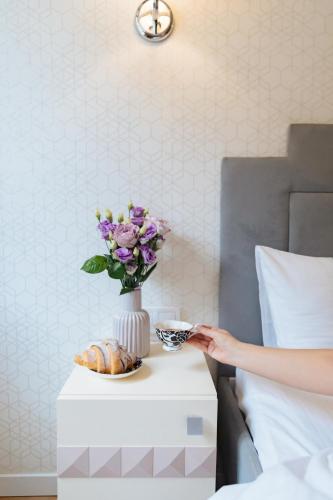 a woman is reaching for a vase of flowers on a table at Art Deco Central Rooms in Lviv