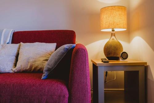 a red chair next to a table with a lamp at The Stable- Hopewell in Bristol