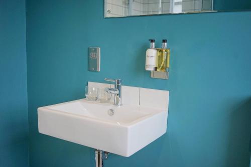 a bathroom with a white sink and a blue wall at The Alma Taverns Boutique Suites - Room 5 - Hopewell in Bristol