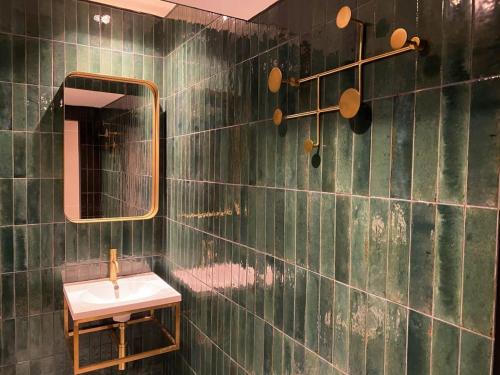 een groene betegelde badkamer met een wastafel en een spiegel bij Modern and Bright Three Bed Apartment in Bristol