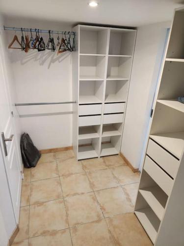 a closet with white shelves and a tile floor at L'étape méditerranéenne logement 4-6 personnes avec parking privé in Sauvian