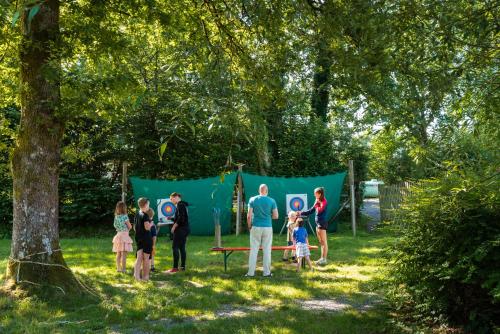 a group of people standing around a table in a park at Camping De Chênefleur in Tintigny