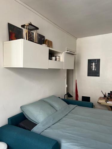 - une chambre avec un lit bleu et des étagères blanches dans l'établissement Charmant studio d'artistes - Paris - Parc des princes - Roland Garros - Trocadero, à Boulogne-Billancourt