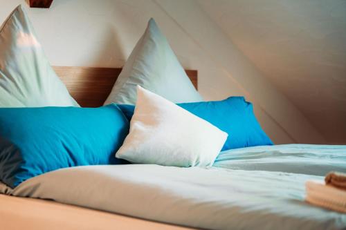 a bed with blue and white pillows on it at Spacious Penthouse with AC and Free Parking Steps Away From the Central Station in Koblenz
