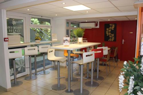 a restaurant with a table and chairs in a room at Premiere Classe St Quentin en Yvelines Elancourt in Trappes