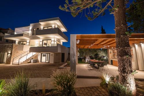 a large white house with a patio at night at Alhena Pavilion in Bouzéïka