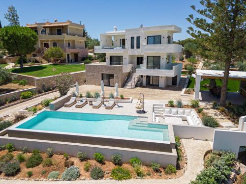 a villa with a swimming pool in front of a house at Alhena Pavilion in Bouzéïka