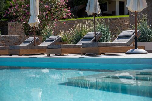 a group of lounge chairs and umbrellas next to a swimming pool at Alhena Pavilion in Bouzéïka