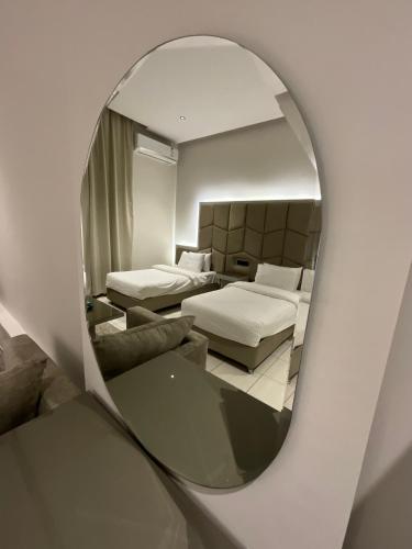 a mirror reflecting a room with two beds and a couch at تاج الملقي للشقق المخدومة in Hail