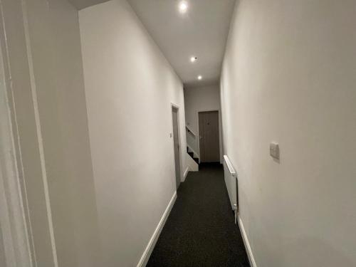 a hallway with a white wall and a white door at Pc homes room C in Hyde
