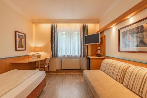 a hotel room with a bed and a desk at Parkhotel Crombach in Rosenheim