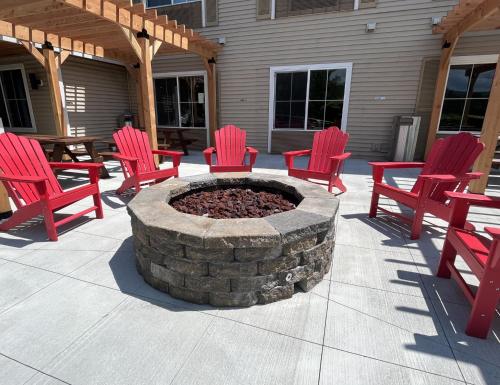 a patio with red chairs and a fire pit at Country Inn & Suites by Radisson, Queensbury - Lake George , NY in Lake George
