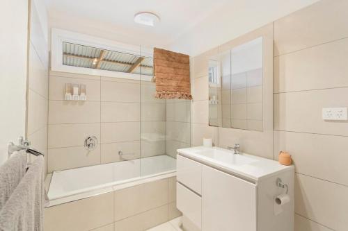 a white bathroom with a tub and a sink and a mirror at Beautiful Bungalow Pet-Friendly & Walk to Beach in Cowes
