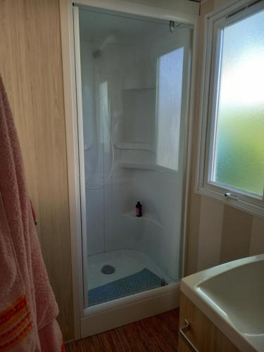 une douche avec une porte vitrée dans une salle de bain dans l'établissement mon bonheur, à Jullouville