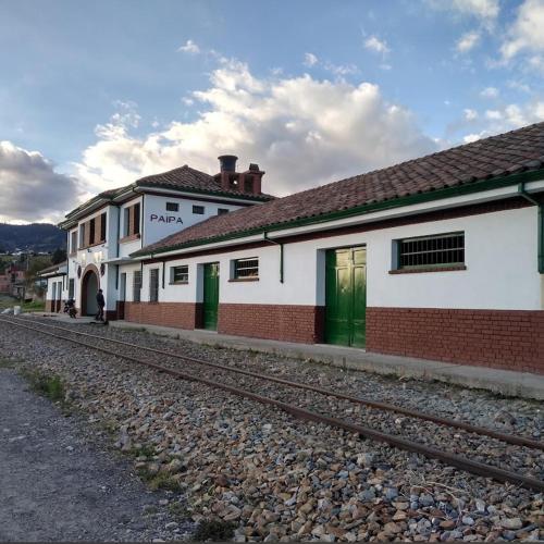a building with green doors next to a train station at Casa de hospedaje Vivaio in Paipa