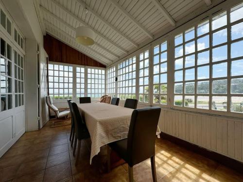 une salle à manger avec une table, des chaises et des fenêtres dans l'établissement Panorama de Morgat I 100m de la mer & Jardin, à Crozon