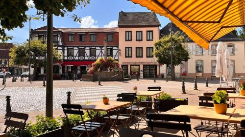 an outdoor patio with tables and chairs and buildings at Hôtel L'Ours De Mutzig in Mutzig