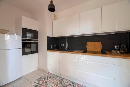 une cuisine avec des armoires blanches et un réfrigérateur blanc dans l'établissement La Vilaine, à Rennes