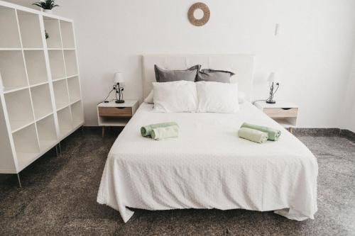 a white bed with two green pillows on it at Marimel Nerja Alojamientos in Nerja