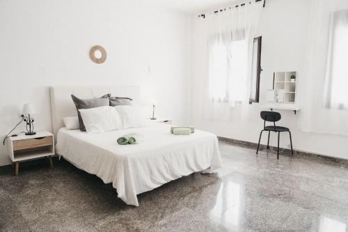 a white bedroom with a white bed and a chair at Marimel Nerja Alojamientos in Nerja
