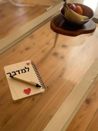 a happy notebook with a pen on a table with a bowl of fruit at למדבר- חווית גלמפינג במדבר in Arad
