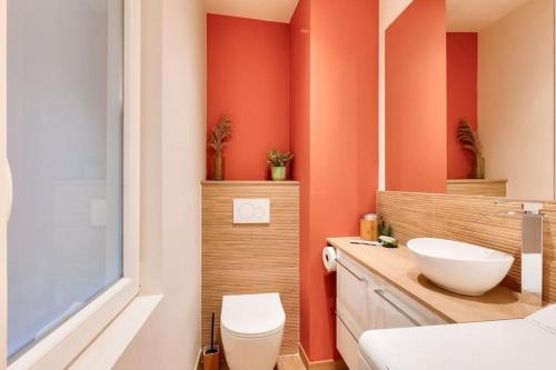 La salle de bains est pourvue de murs orange, de toilettes et d'un lavabo. dans l'établissement 2BR flat near Louis Pradel metro station, à Lyon