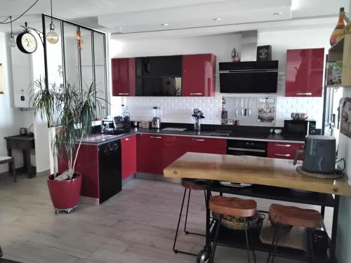 une cuisine avec des placards rouges et une table en bois dans l'établissement PESSIC'art, à Nice