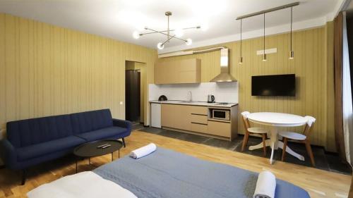 Una sala de estar con un sofá azul y una cocina. en Comfortable Studio In Tbilisi, en Tiflis