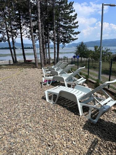 a row of white lounge chairs on a beach at Borova bajka in Usije