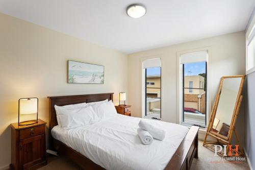 a bedroom with a bed with white sheets and two windows at Cowes 3Bdr-2Bt Family TownHouse in Cowes