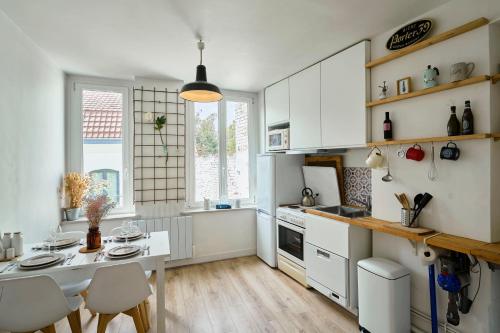 une cuisine avec des armoires blanches et une table et des chaises dans l'établissement Le Refuge - Les Demeures d'Adrien, à Lille
