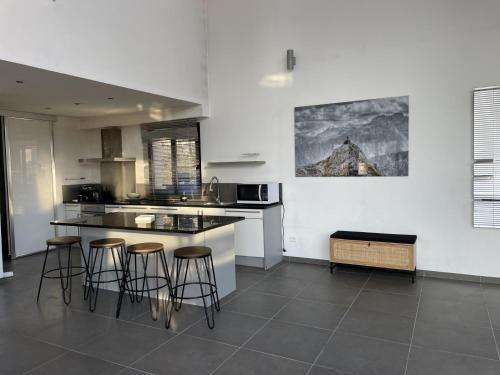 une cuisine avec trois tabourets de bar et un comptoir dans l'établissement Luxueux duplex avec vue panoramique sur Notre-Dame, à Marseille