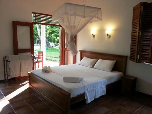 a bedroom with a bed and a large window at Hettimulla River House in Bentota
